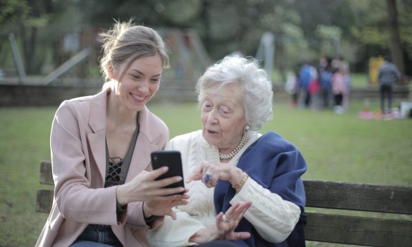 Cheerful senior mother and adult daughter using smartphone together