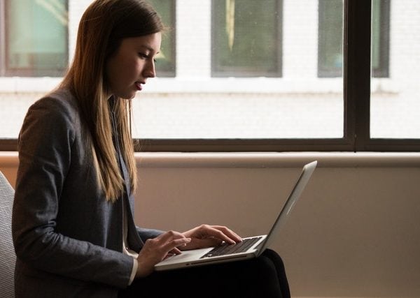 Woman Sitting Down and Using Laptop on Her Lap