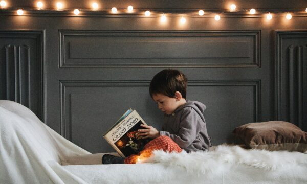 Stock photo of kid reading in bed